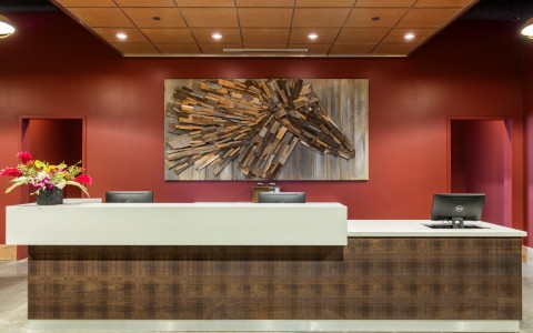 Reception of a hotel with features as a red wall, elegant big paint and three desktops at nighttime