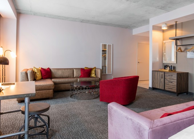 Corner view of a king suite living room area with features as comfy sofas, study desk and a mirror on the wall at nighttime