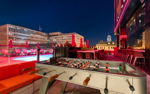 Closeup view of rooftop with a swimming pool and a futbolito table in red light at night
