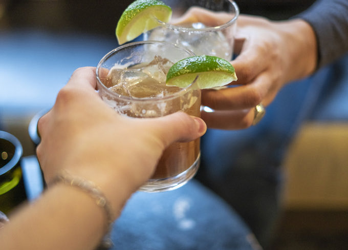Closeup view of a lady and a guy making a toast with a cocktail