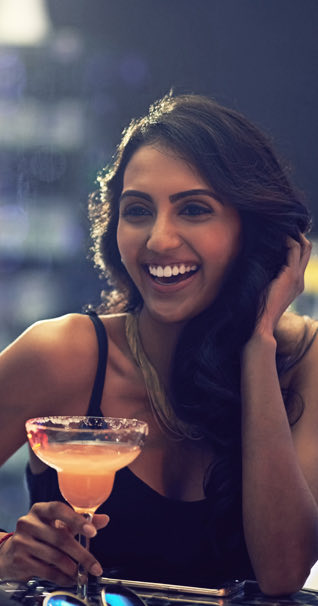 Young lady laughing while she is holding a margarita 