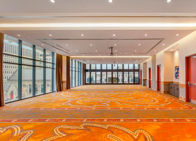 View of a empty spacious hotel room with a orange carpet and a great outside view