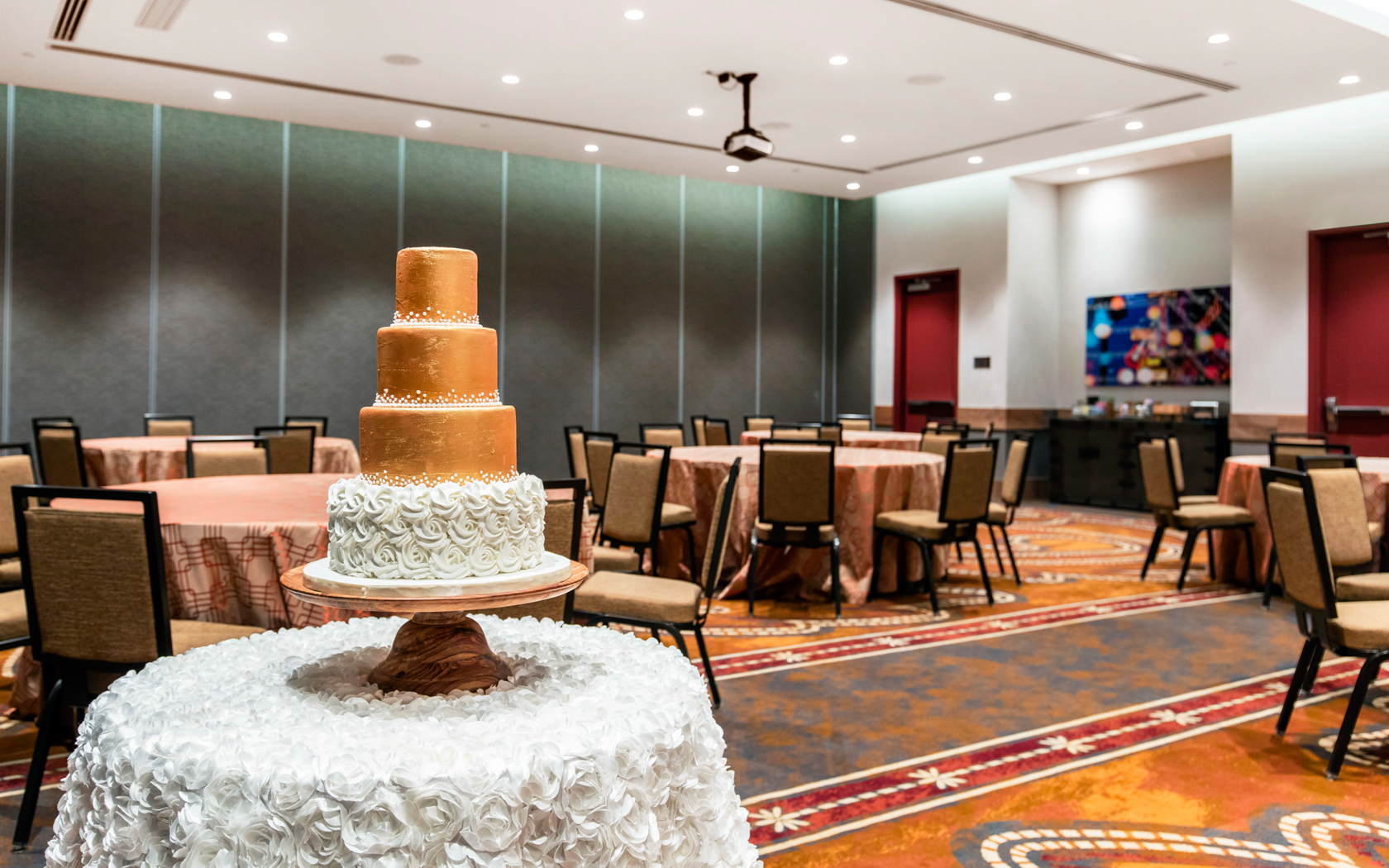 gallery View of a empty events room of a hotel with a three tier cake in the table