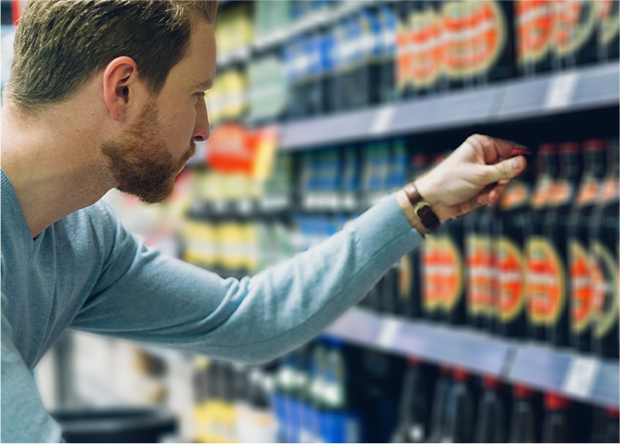 A guy picking a bottle in the supermarket 