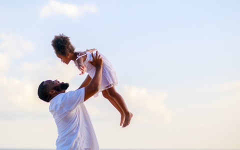 a man holding her daughter in the air 