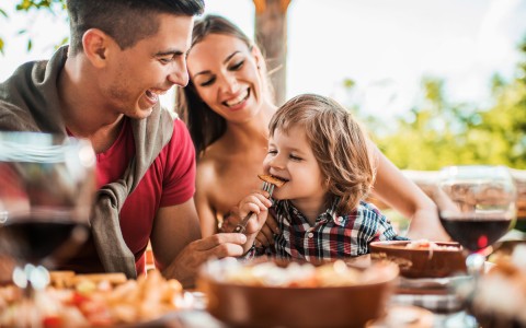little boy eating bite of pizza with parents