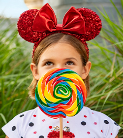girl with red mickey eats and giant rainbow lollipop