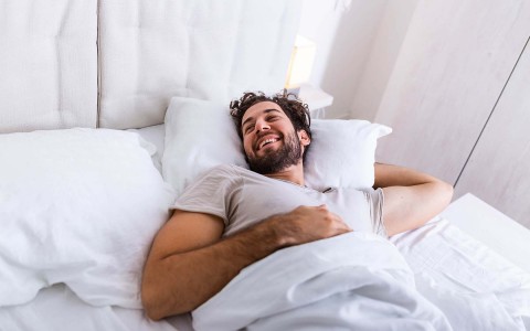 man laying in a hotel bed 