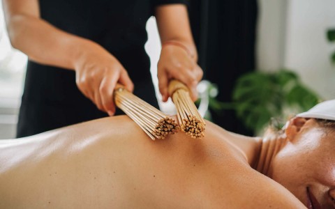 woman receiving a back massage with massage sticks