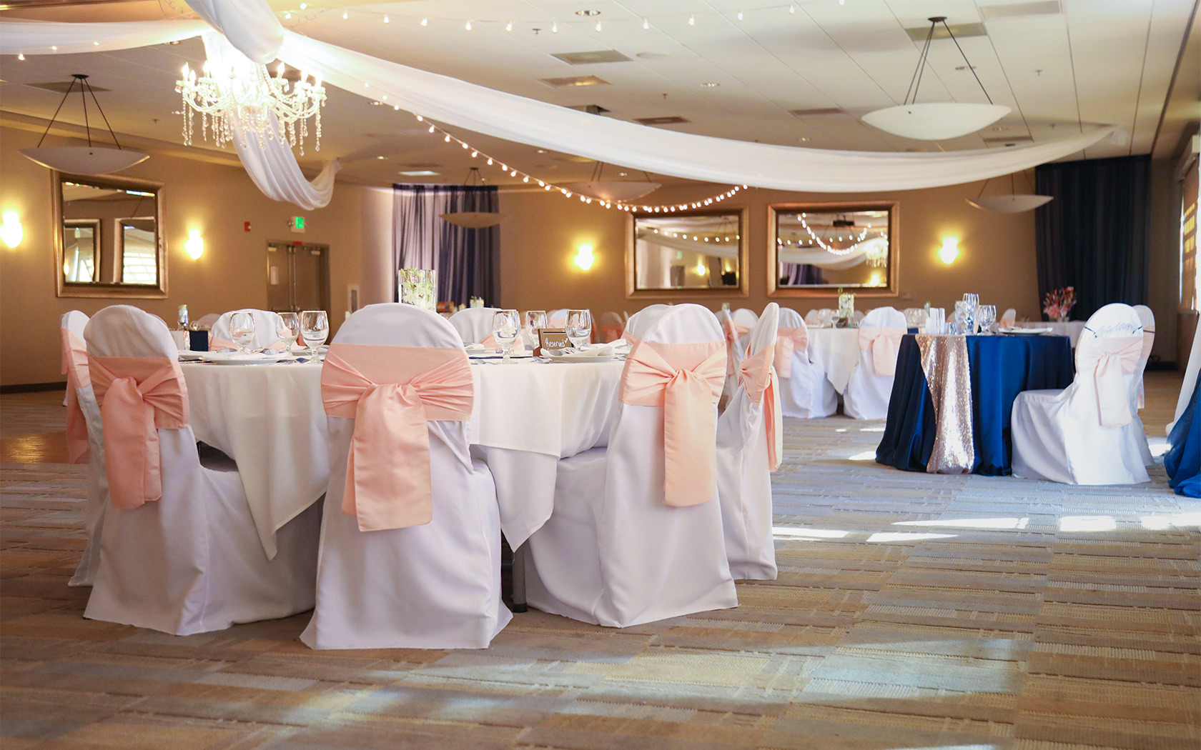 tables with white table clothes and chairs with pink bows