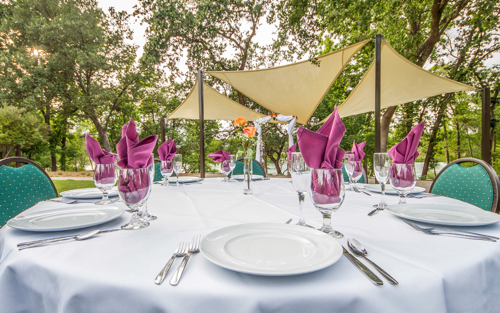 table outside set with plates, silverware, and glasses with napkins in them