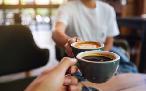 close view of two people toasting with coffee cups