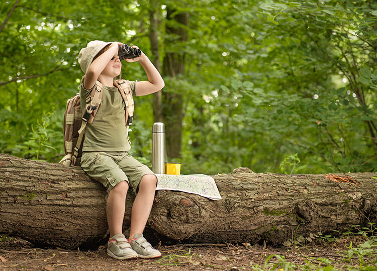 a boy explorer looking through the binoculars