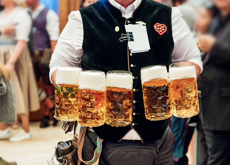 a man holding five glasses of beer