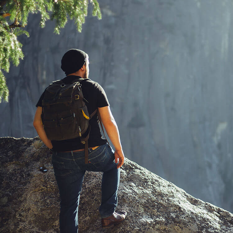 back view of a man with a backpack standing on a rock