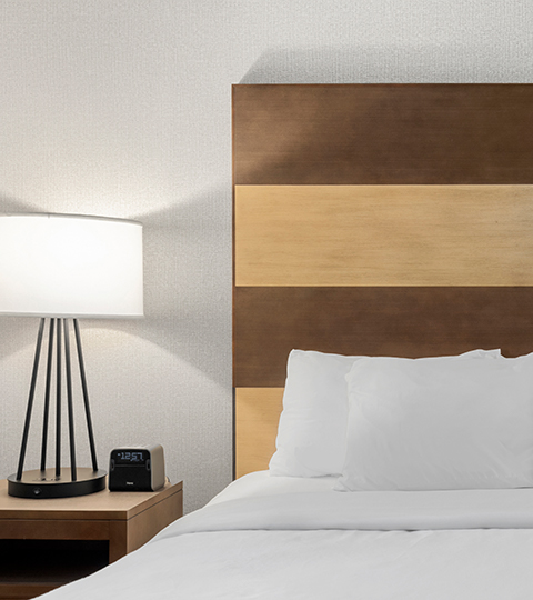 view of a hotel bed with wooden headboard 