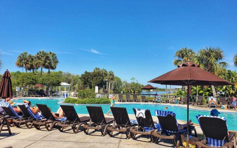 panoramic view of a pool area of property with all the stuff setup and some guests enjoying it 