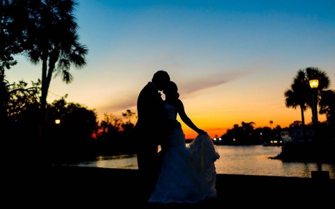 shadow figures of a bride and groom kissing at sunset 