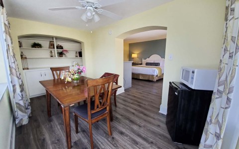 suite room view of property with features as a microwave, mini fridge, small table and a ceiling fan