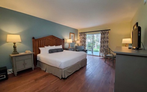 view of the hotel bedroom with features as a king bed size, two nightstands, small tv and a private balcony