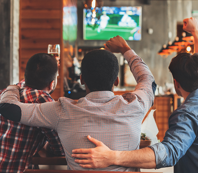 three guys gathered cheering at a pub
