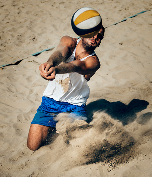 guy ready to kick volleyball ball in the sand