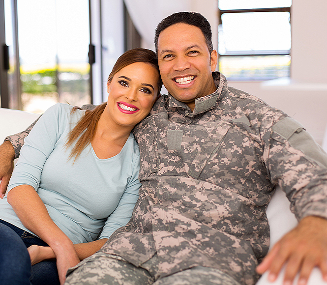 militar guy hugging his wife looking straight to the camera 