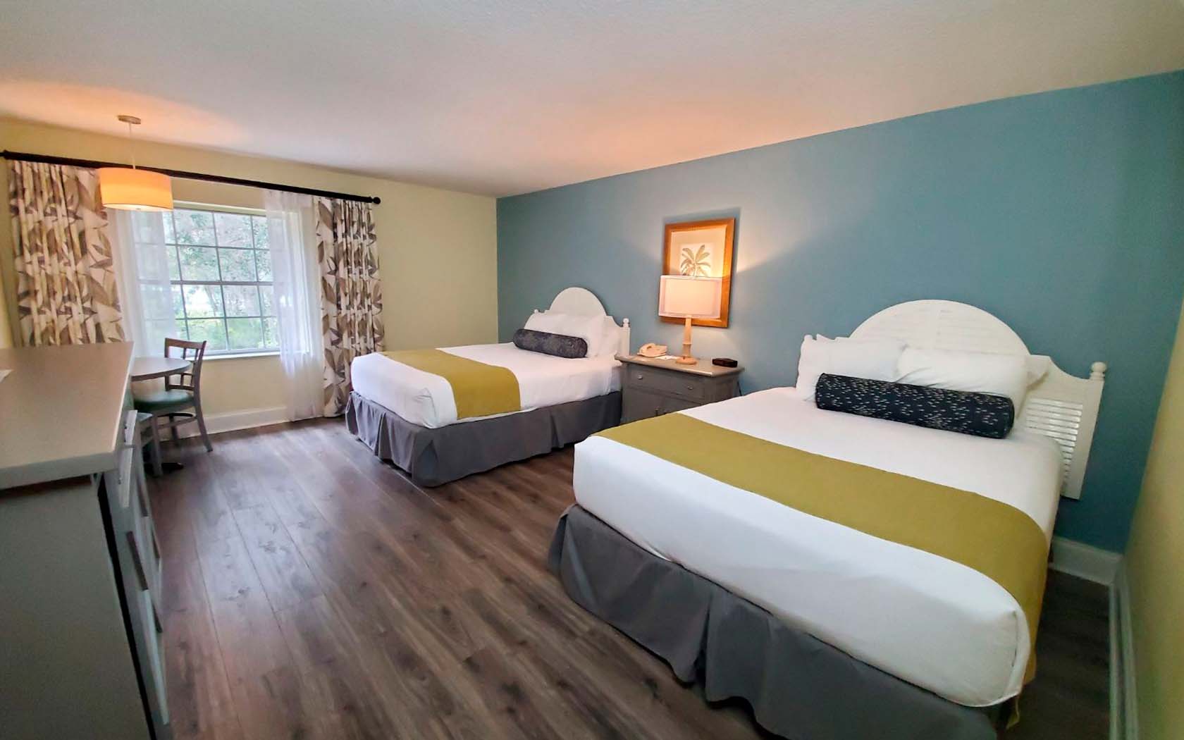 view of cozy double hotel bedroom with features as a two double beds, nightstand and a paint on the wall