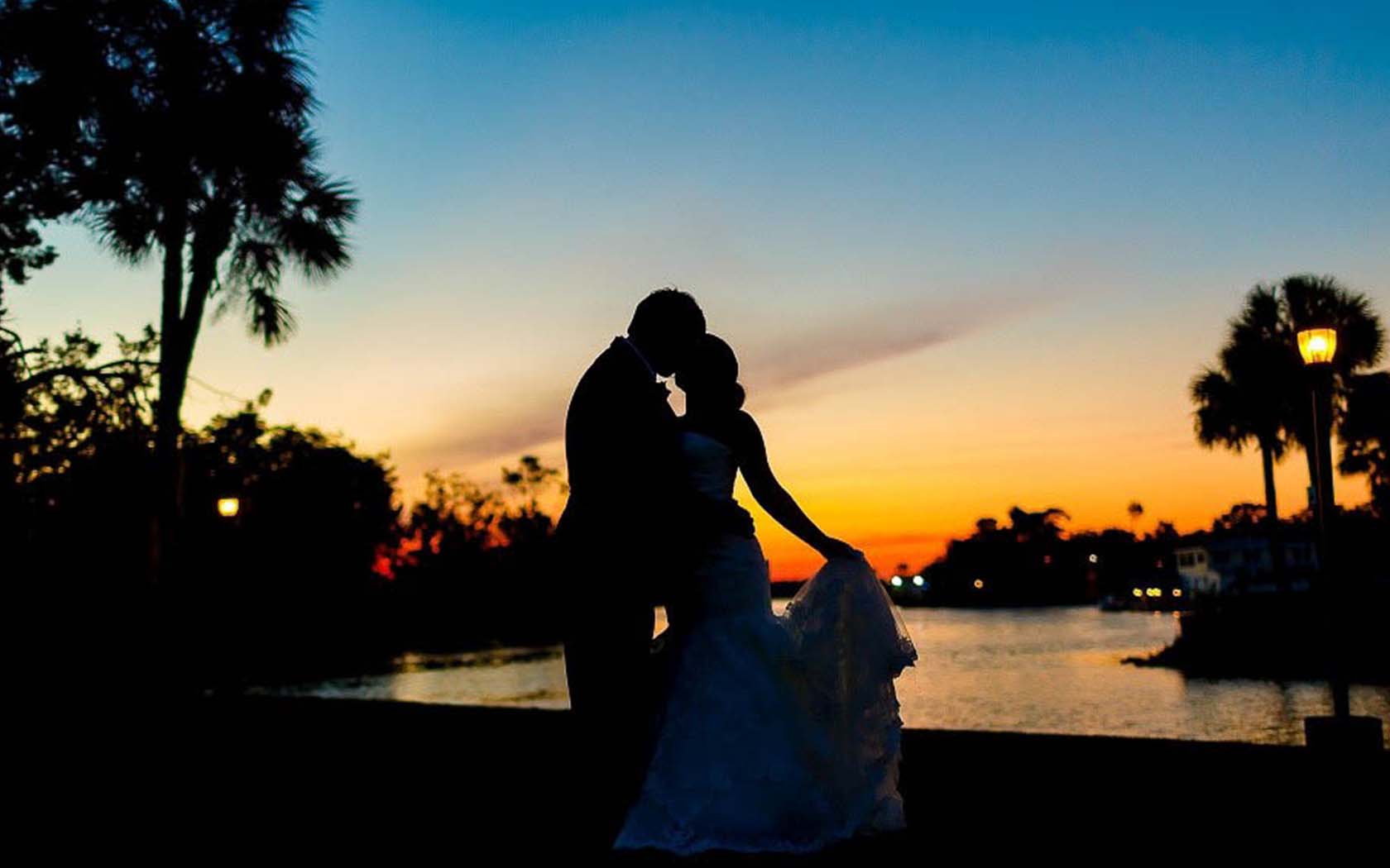 shadow figures of a bride and groom kissing at sunset 