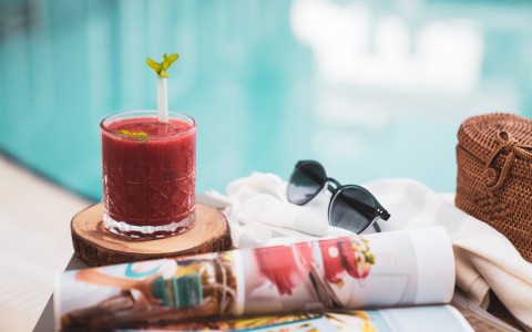 view of a beverage, a magazine and sunglasses poolside