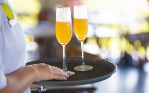 close view of a man holding a tray with two cocktail glasses