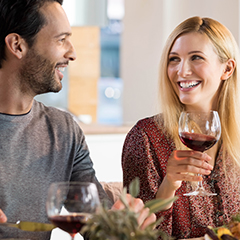 a man and a woman smiling and drinking wine